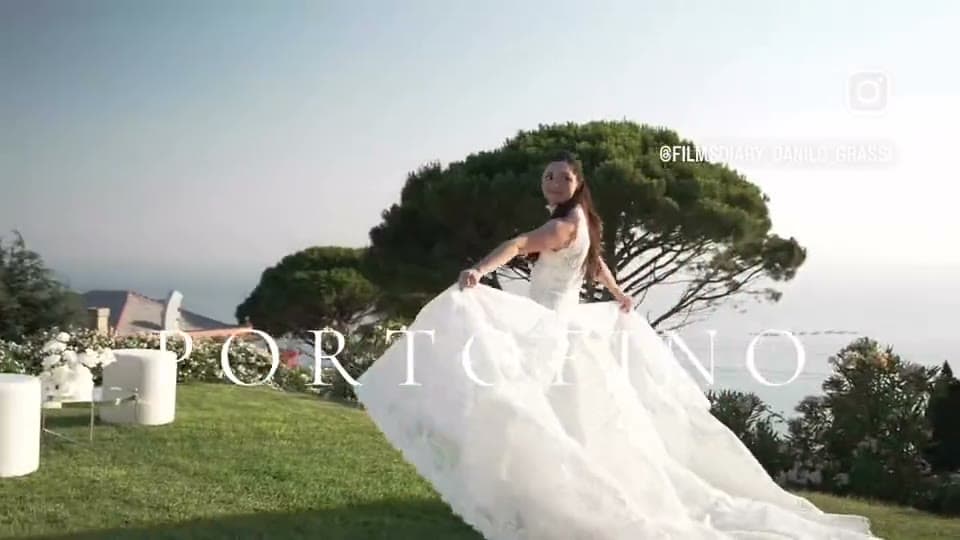 A bride on a clifftop lawn above the sea in Portofino, the train of her gown swept out behind her