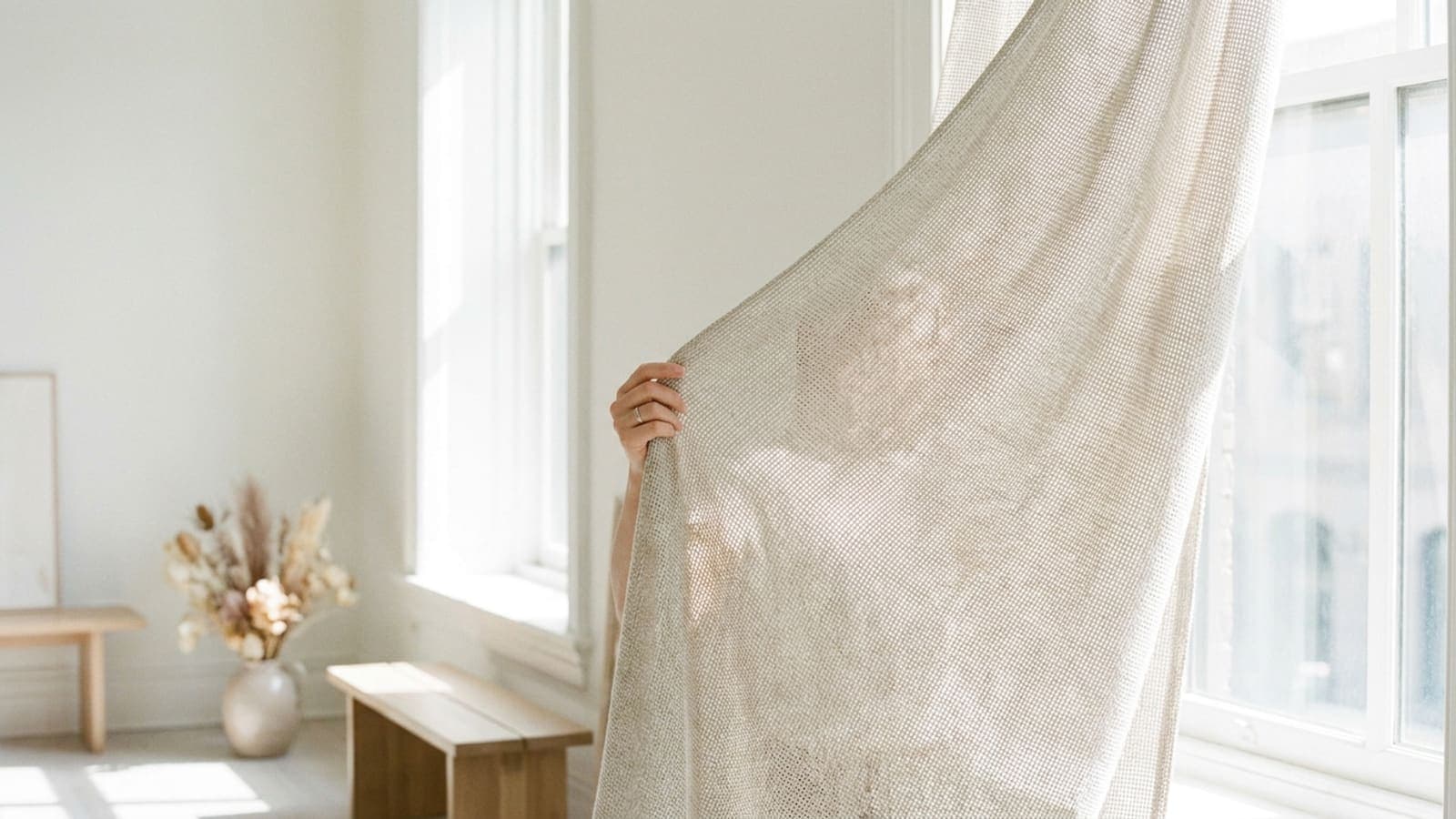 Pale high-twist wool draped over a chair by an open window, light passing through the open weave