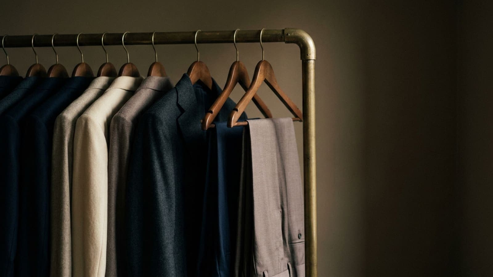 A wardrobe rail of jackets and trousers with three garments pulled forward from the rest