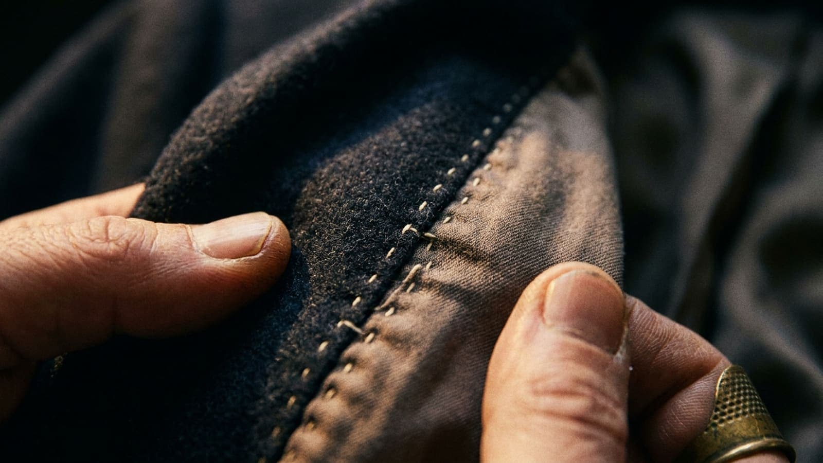 A jacket turned inside out, a hand holding open the seam allowance at the centre back